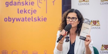 Powiększ grafikę: Prezydent Gdańska mówi do mikrofonu. W tle baner promujące gdańskie lekcje obywatelskie