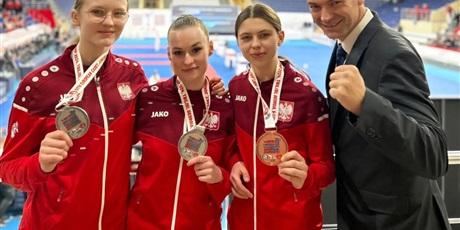 Powiększ grafikę: Trzy zawodniczki z medalami i trenerem