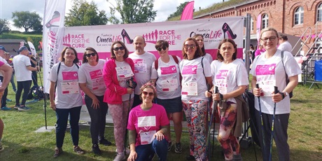 Powiększ grafikę: Grupa nauczycielek w strojach startowych Race for the Cure na tle baneru promującego akcję